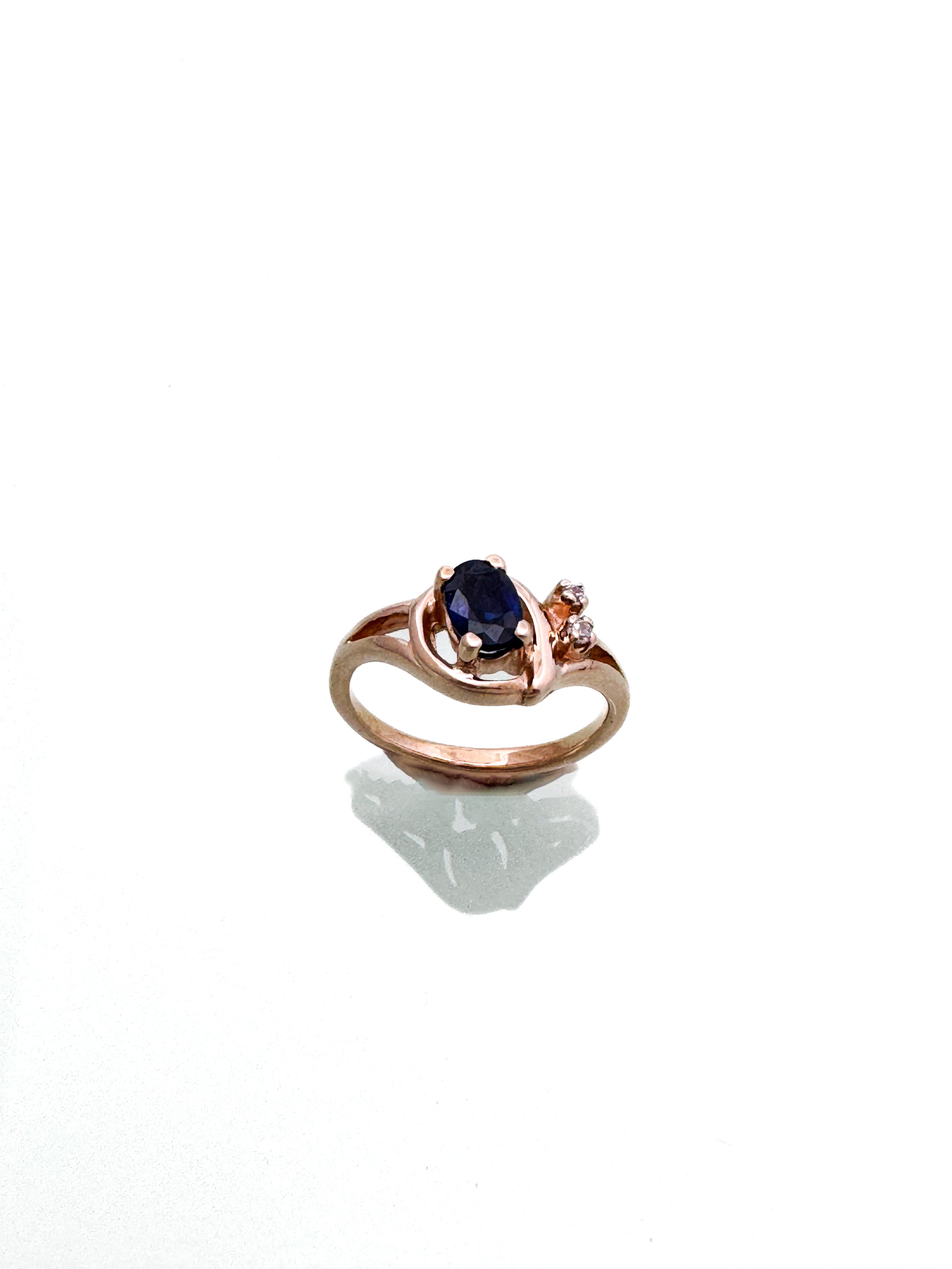 טבעת רוז גולד 14 קארט במרכז אבן חן כחולה בצד זירקונים